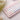 Small keyboard with cute pink keycaps pastel keys on a textured surface with flowers in the background